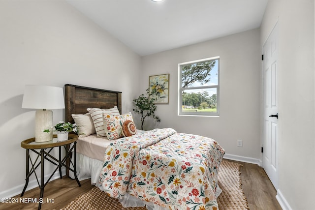 bedroom with vaulted ceiling and dark hardwood / wood-style floors