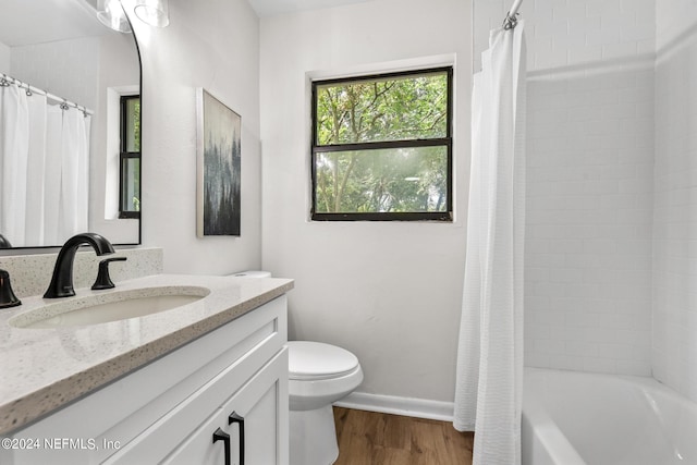 full bathroom with hardwood / wood-style flooring, vanity, shower / bath combination with curtain, and toilet