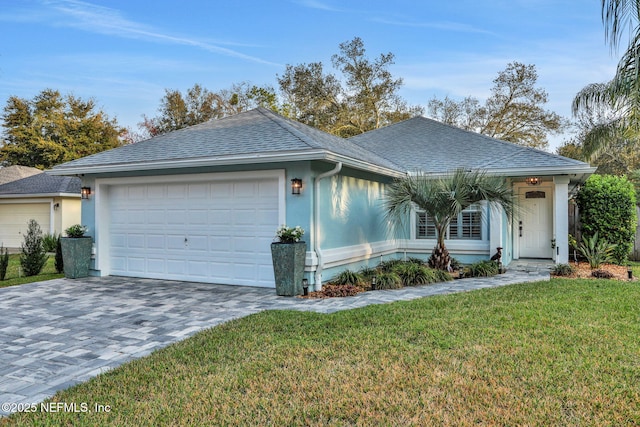 single story home featuring a garage, decorative driveway, roof with shingles, stucco siding, and a front yard