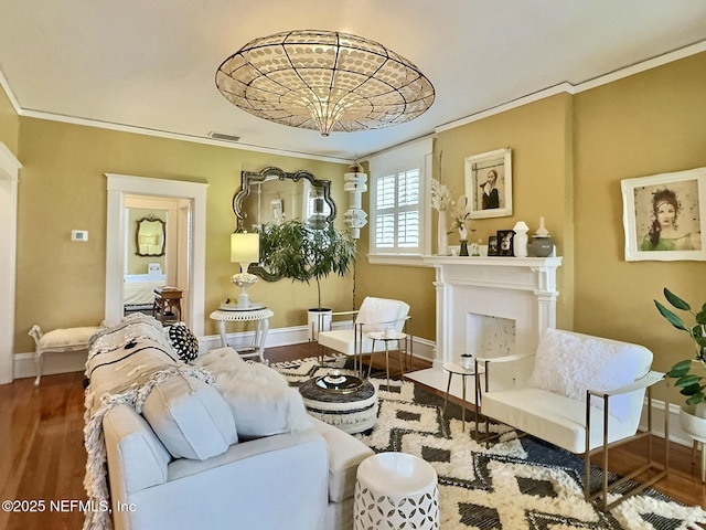 living area with hardwood / wood-style flooring, ornamental molding, and a notable chandelier