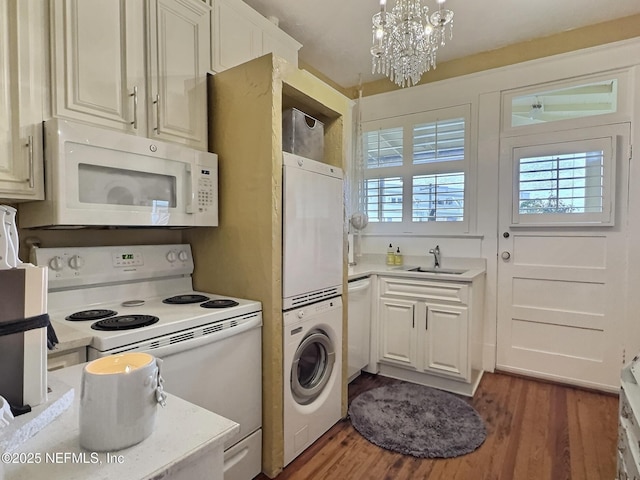 kitchen featuring sink, dark hardwood / wood-style flooring, stacked washer and dryer, hanging light fixtures, and white appliances