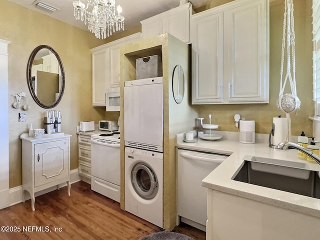 kitchen featuring sink, white appliances, dark wood-type flooring, stacked washer and clothes dryer, and white cabinets