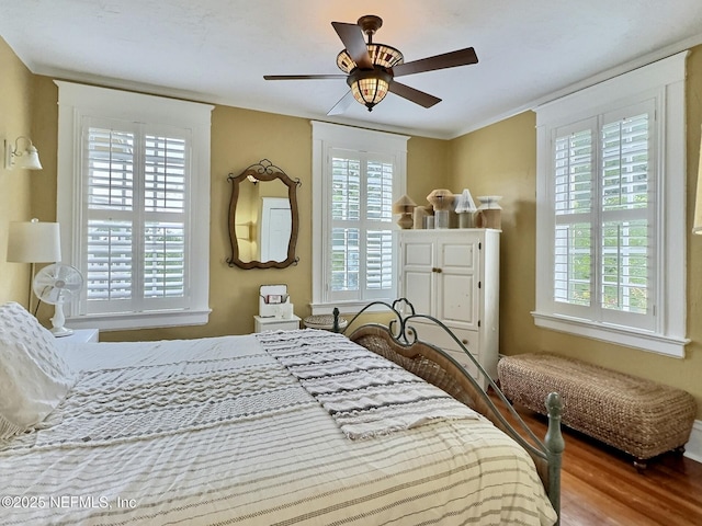 bedroom featuring wood-type flooring, ceiling fan, and crown molding