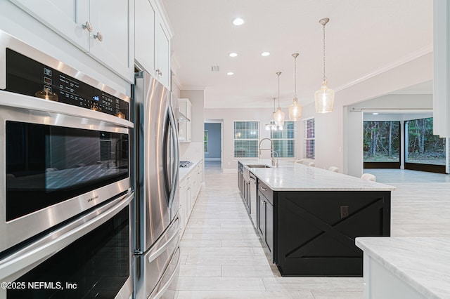 1351 Weaver Glen Rd, Jacksonville, FL 32223 - kitchen featuring stainless steel appliances, white cabinets, light stone countertops, a center island with sink, and pendant lighting