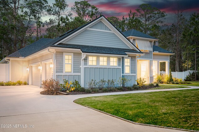 1351 Weaver Glen Rd, Jacksonville, FL 32223 - view of front of property featuring a shingled roof, a lawn, concrete driveway, an attached garage, and board and batten siding