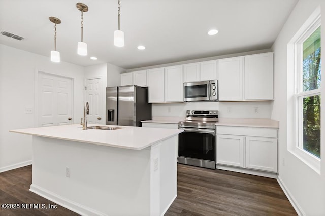 kitchen featuring a kitchen island with sink, sink, pendant lighting, and stainless steel appliances