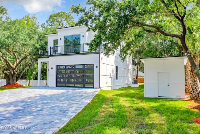 view of front of property with a garage, central AC, a front yard, and a balcony