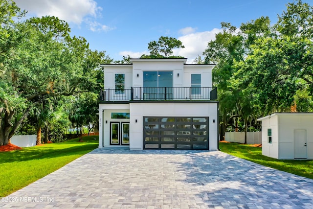 back of house with a garage, a balcony, and a yard