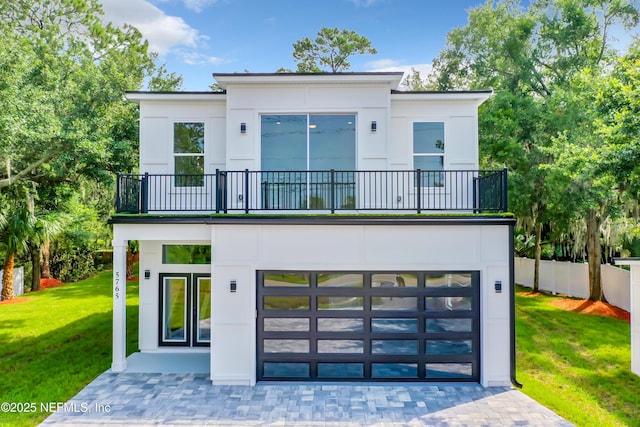 back of property with a yard, a garage, and a balcony