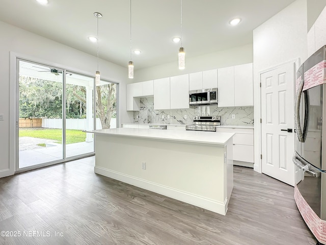 kitchen with white cabinetry, hanging light fixtures, stainless steel appliances, a center island, and tasteful backsplash