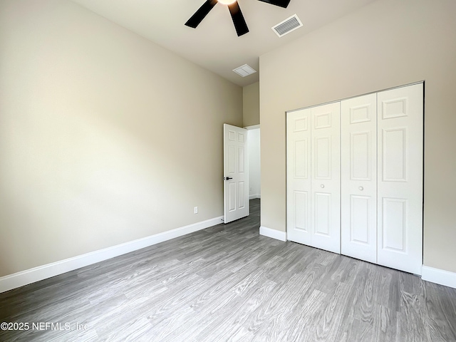 unfurnished bedroom with ceiling fan, light hardwood / wood-style floors, a closet, and a high ceiling