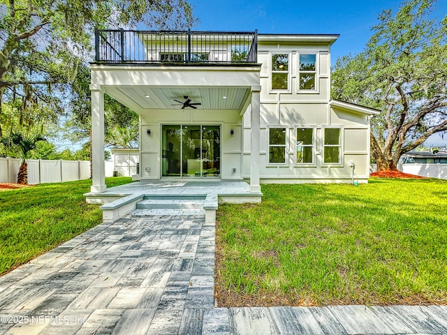 rear view of property with a balcony, a yard, ceiling fan, and a patio area