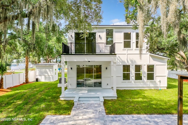 back of property featuring a balcony, a yard, cooling unit, and a storage unit