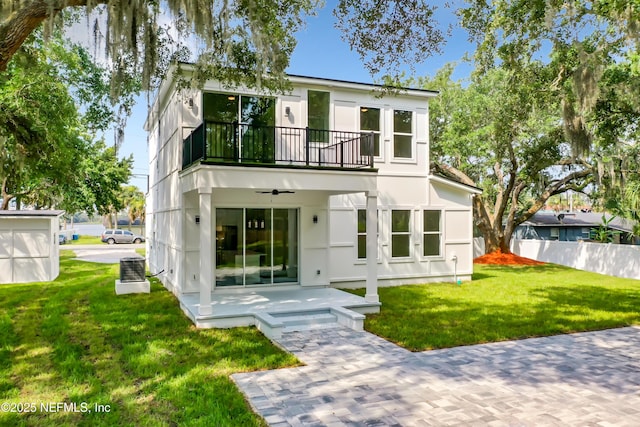 back of property with a balcony, a patio area, ceiling fan, and a lawn