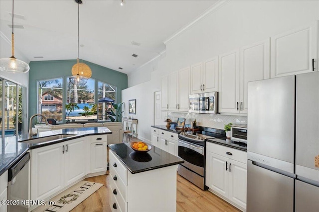 kitchen with sink, hanging light fixtures, stainless steel appliances, white cabinets, and a kitchen island