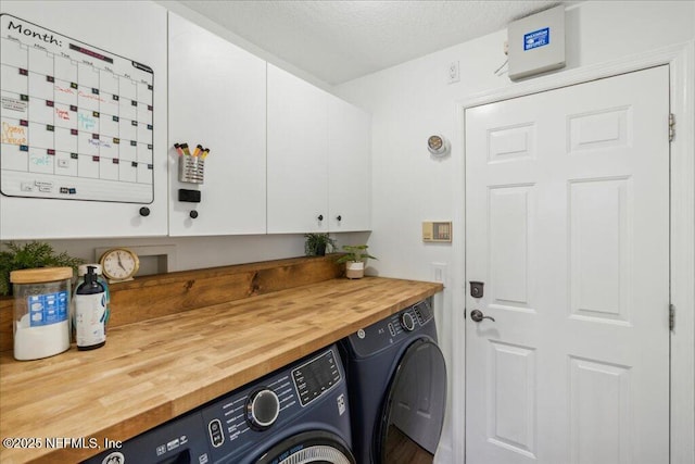 laundry area with separate washer and dryer, cabinets, and a textured ceiling