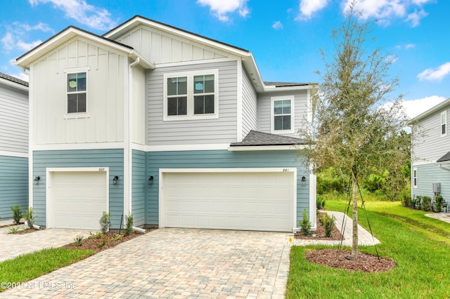 view of front of home with a garage, decorative driveway, a front lawn, and board and batten siding