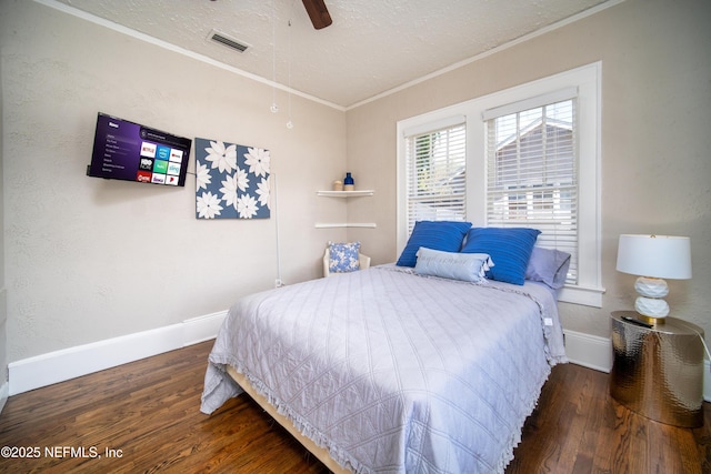 bedroom featuring a textured ceiling, ornamental molding, wood finished floors, and visible vents