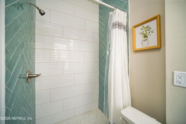 full bathroom featuring tiled shower and toilet