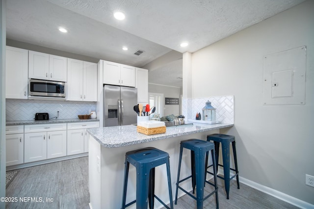 kitchen with visible vents, appliances with stainless steel finishes, light wood finished floors, and electric panel