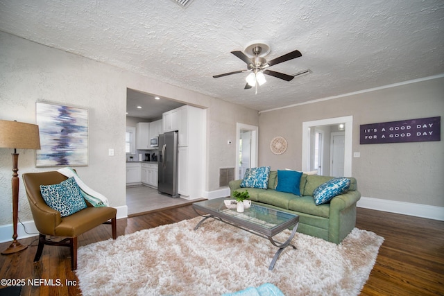 living room featuring a textured ceiling, a textured wall, wood finished floors, visible vents, and baseboards