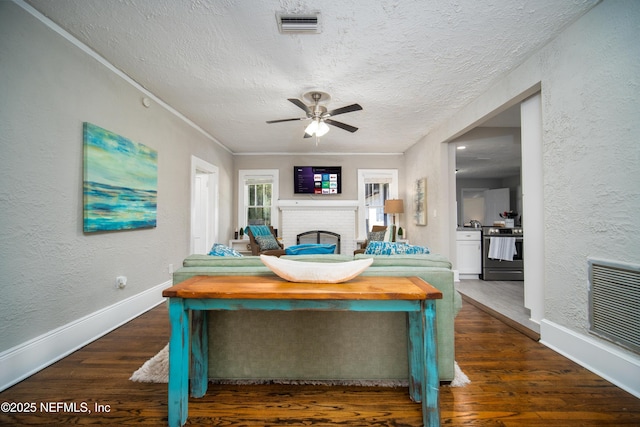 interior space with a fireplace, visible vents, a textured wall, a textured ceiling, and wood finished floors