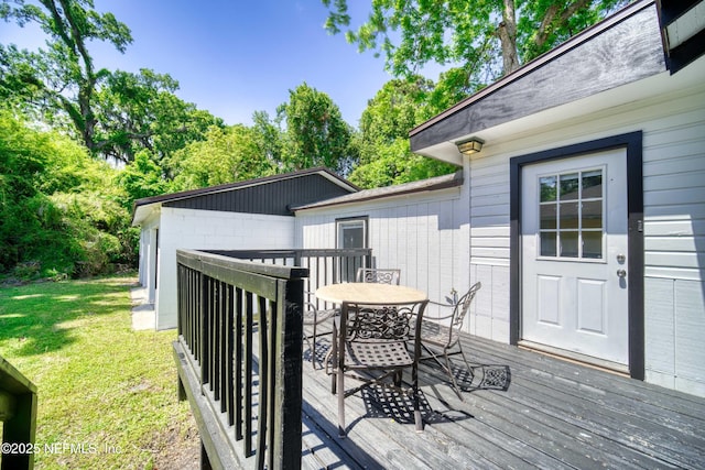 wooden deck with a yard and outdoor dining space