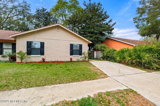 ranch-style house with a front yard, fence, and stucco siding