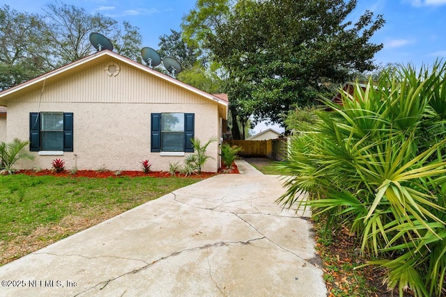 view of home's exterior with a yard, fence, and stucco siding