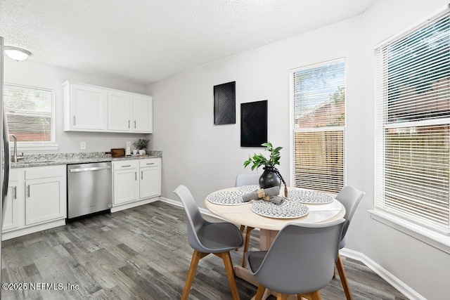 dining space with a textured ceiling, light wood-style flooring, and baseboards