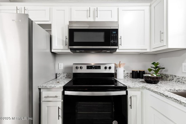 kitchen featuring appliances with stainless steel finishes, white cabinetry, and light stone counters