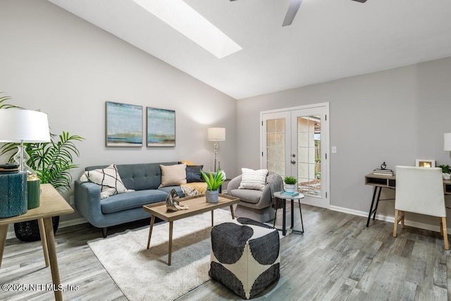 living area featuring french doors, lofted ceiling with skylight, a ceiling fan, wood finished floors, and baseboards