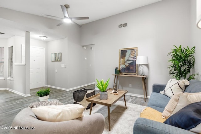 living area with ceiling fan, wood finished floors, visible vents, and baseboards