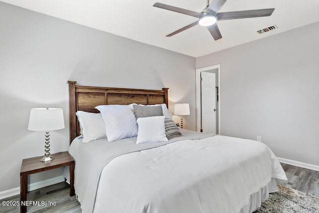 bedroom featuring a ceiling fan, baseboards, visible vents, and wood finished floors