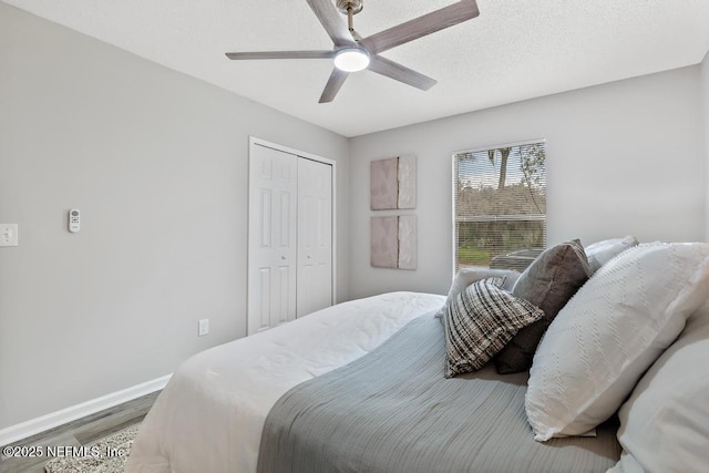 bedroom featuring a closet, a ceiling fan, a textured ceiling, wood finished floors, and baseboards