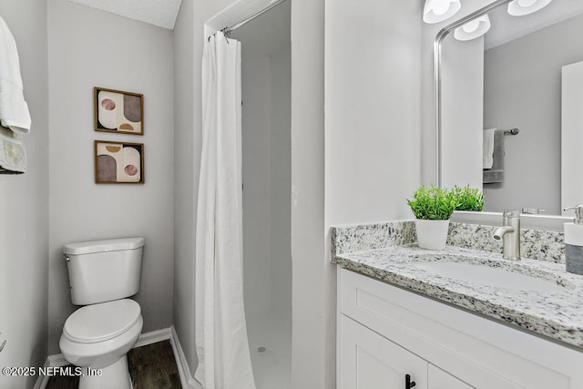 bathroom featuring a stall shower, vanity, toilet, and baseboards