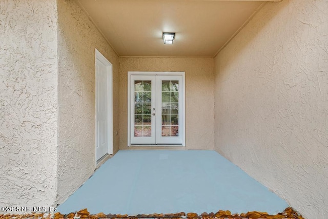 view of exterior entry featuring french doors and stucco siding