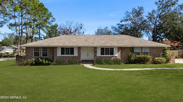 ranch-style home with brick siding, a front yard, and roof with shingles