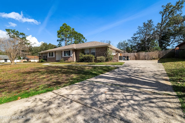 single story home with brick siding, concrete driveway, a front lawn, and fence