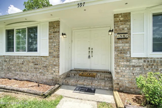 view of exterior entry featuring covered porch and brick siding