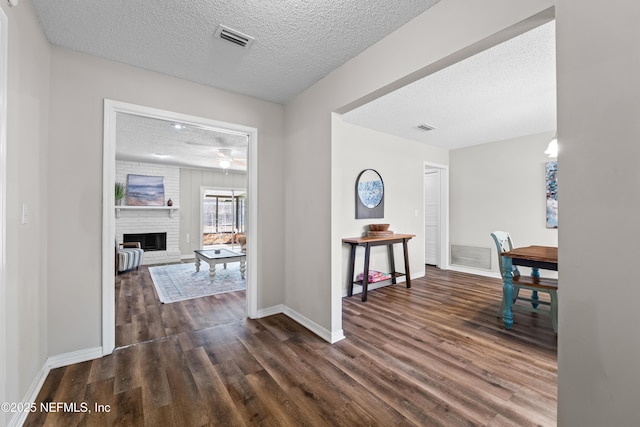 hall featuring visible vents, a textured ceiling, and dark wood-type flooring