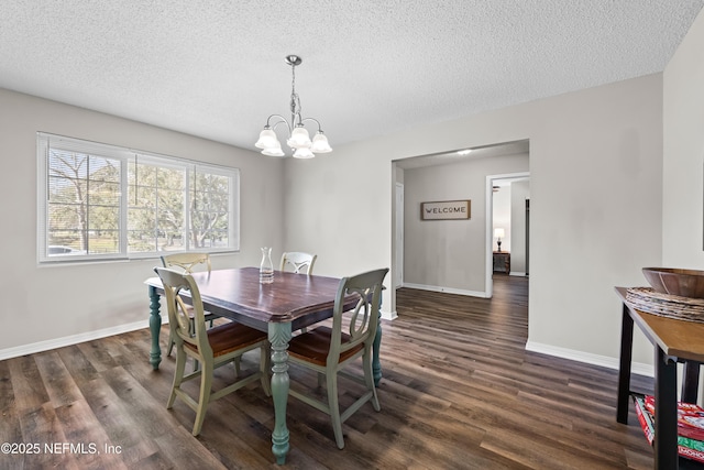 dining area with baseboards, dark wood-type flooring, an inviting chandelier, and a textured ceiling