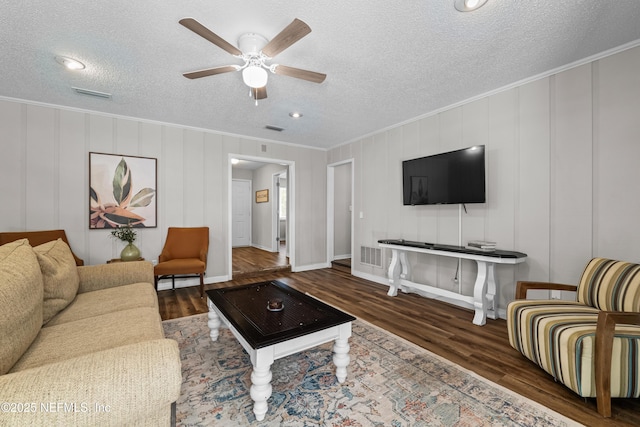 living room featuring a ceiling fan, crown molding, wood finished floors, and visible vents