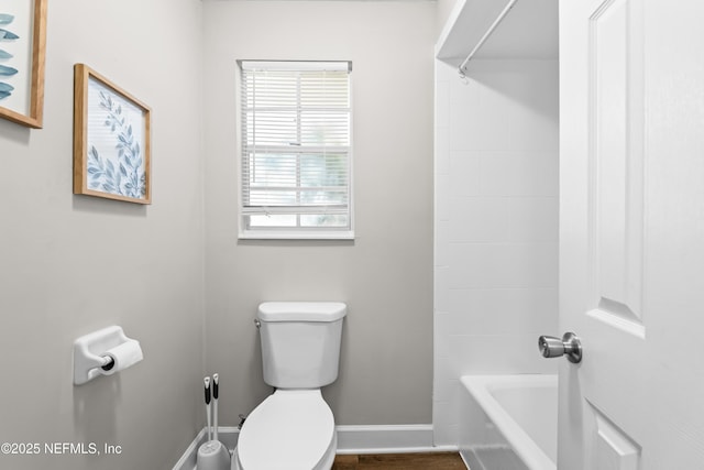 bathroom with bathing tub / shower combination, toilet, and baseboards