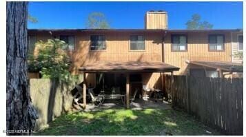 back of property featuring a chimney and fence