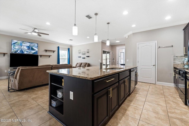 kitchen featuring sink, decorative light fixtures, dishwasher, light stone countertops, and a kitchen island with sink