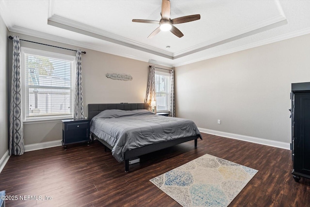 bedroom with crown molding, dark hardwood / wood-style floors, ceiling fan, and a tray ceiling