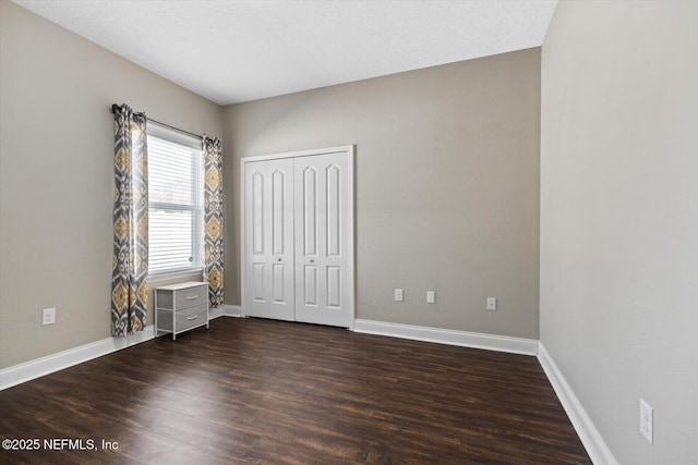 unfurnished bedroom with dark hardwood / wood-style flooring and a closet