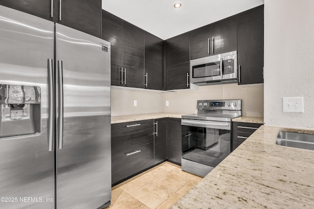 kitchen with stainless steel appliances, light stone countertops, sink, and light tile patterned floors