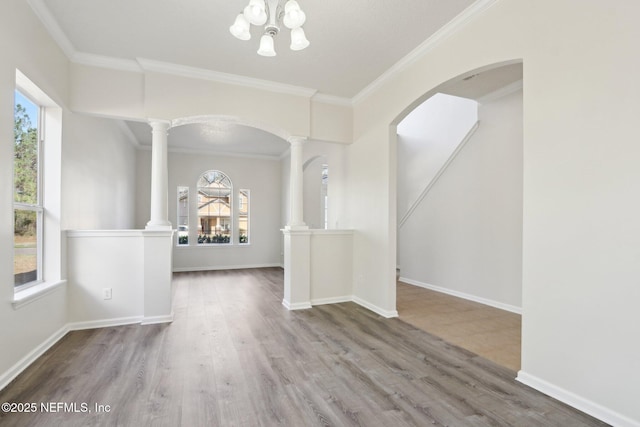 unfurnished room featuring hardwood / wood-style floors, crown molding, and ornate columns